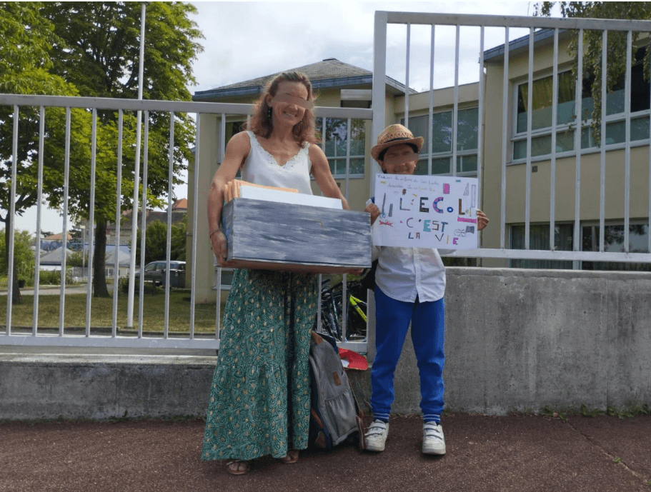 The little boy and his teacher, standing in front of the school, with the schools supplies box and a poster "School is Life" © The United Children